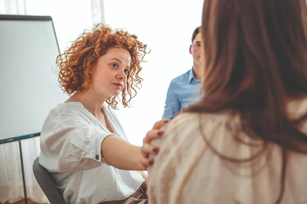 An adult woman comforting her friend during a support group session