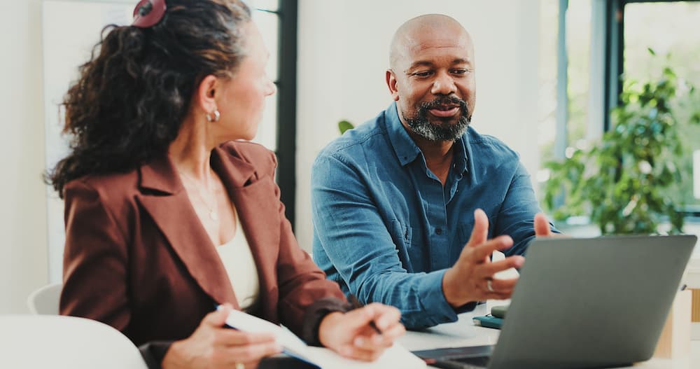 Two people sitting in front of a laptop